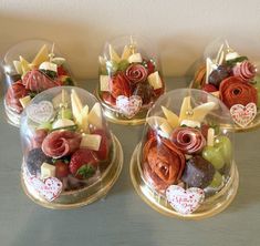 four glass bowls filled with assorted candies and fruit on top of a table