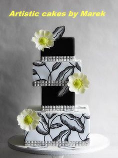 a black and white wedding cake with flowers on the top is featured against a gray background