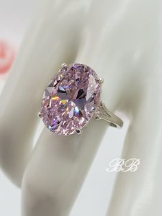 This Bohn Beauty features a huge 5A quality light pink oval cut cubic zirconia stone in a 925 unplated sterling silver solitaire ring setting. Made to order. Please allow 3 weeks for the production of your ring. Weight: 17.46 Carats Gem Type: Lab Created Cubic Zirconia Shape: Oval Cut Size: 16x12MM Color: Light Pink Quality: 5A Hardness: 8.5 Mohs Did you know there are different grades of cubic zirconia? (A - 6A) The higher the grade, the better the material, polish and more accurate the cut. Mo Pink Oval Diamond Cut Jewelry, Dazzling Oval Pink Ring, Pink Oval Diamond Ring With Dazzling Style, Dazzling Pink Oval Diamond Ring, Dazzling Pink Oval Ring, Dazzling Oval Cubic Zirconia Rings, Dazzling Oval Sterling Silver Diamond Ring, Oval Diamond Cut Cubic Zirconia Rings, Pink Oval Diamond Ring With Vs Clarity