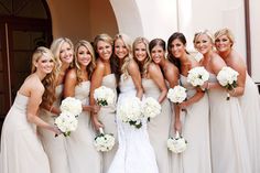 a group of women standing next to each other in front of a building holding bouquets