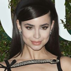 a close up of a person wearing a black dress and diamond earrings on her head