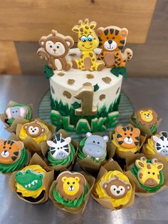 cupcakes decorated with jungle animals and giraffes are sitting in front of a cake