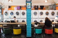 a woman sitting at a table in front of a row of washers