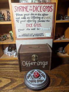 a wooden box sitting on top of a table next to a sign that says shrine of the dicegods