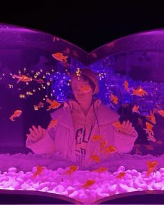 a man standing in front of a fish tank with his hands out to the side