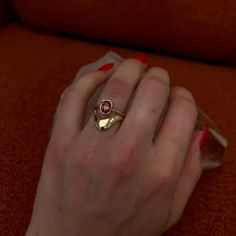 a woman's hand wearing a gold ring with a pink tourmaline stone