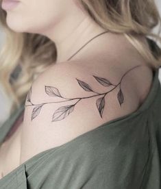 a woman's shoulder tattoo with leaves on her left arm and the top half of her body