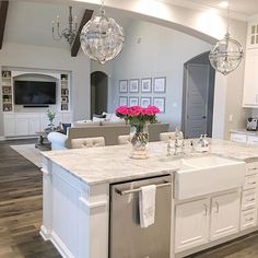 a large kitchen with white cabinets and marble counter tops is pictured in this image, there are chandeliers hanging from the ceiling