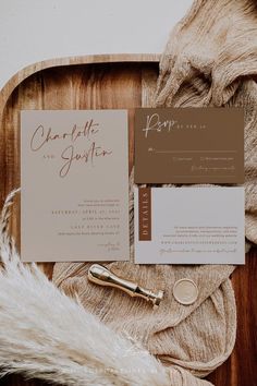 the wedding stationery is laid out on a wooden tray