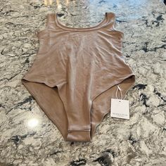 a women's tan tank top with a tag on the front sitting on a marble countertop