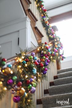 christmas decorations on the banisters and stairs are decorated with colorful balls, pine cones, and garland