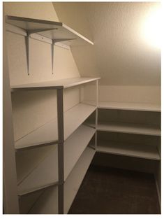 an empty white closet with shelves and lights