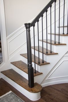 a set of stairs with black railings and wood treading on the bottom handrail