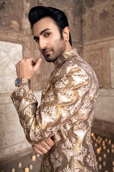 Gold Sherwani Dress for Pakistani Groom Dresses is an Antique gold jodhpur sherwani with boti of Resham worn with complimenting gold tailored pants. The jacket is enhanced with an accent of ivory. Paired with matching shoes. Gold Sherwani: The Men's Sherwani in a pretty gold shade is emblazoned with lavish design and embroidered work. The Sherwani is perfectly stitched as per the customer's choice and it comes in premium quality fabric. Intricate designs and fine details of the embroidery make t Gold Sherwani With Dupatta In Raw Silk, Gold Sherwani With Dupatta For Reception, Gold Traditional Wear With Naqshi Drape, Traditional Gold Raw Silk Wear With Naqshi, Gold Salwar Kameez For Reception With Straight Kurta, Gold Straight Kurta For Reception, Traditional Gold Unstitched Suit With Naqshi Detailing, Traditional Gold Unstitched Suit With Naqshi, Gold Kurta With Dupatta For Reception