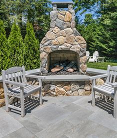 an outdoor fireplace with two chairs around it