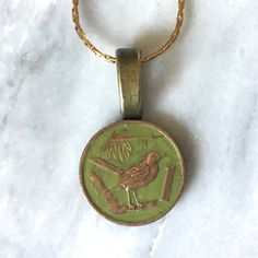 Hand Painted one cent Cayman Island coin necklace. The coin features a Thrush bird.  The background is painted green. Carefully sealed.  Beautiful detail. Chain length is 16 inches.  Bail and chain necklace are gold toned metal (costume jewelry). Please visit my shop for more hand painted coin pendants and coin pendant necklaces and unique jewelry! I combine shipping.  Any displays not included in sale unless otherwise noted. Coin in photo for size reference. Feel free to reach out with any questions, thank you for visiting my shop! All orders will be securely packaged. Metal Costume, Cayman Island, One Coin, Coin Pendant Necklace, Coin Jewelry, Coin Necklace, Coin Pendant, Gold Tone Metal, Chain Length