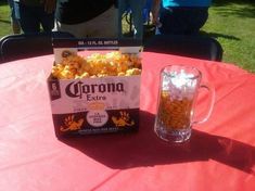 a box of popcorn sitting on top of a table next to a glass mug filled with corn