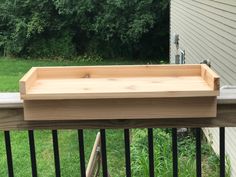 a wooden planter sitting on top of a metal rail next to a grass covered yard