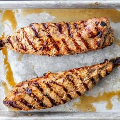 two grilled steaks sitting on top of a pan