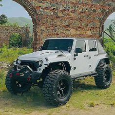 a white jeep parked in front of an old brick building