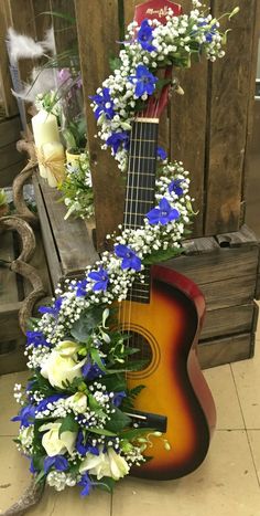 a guitar decorated with blue and white flowers sits in front of a wooden box on the floor