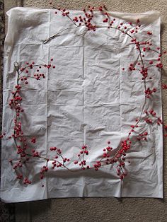 a piece of white paper with red berries on it sitting on top of a carpeted floor