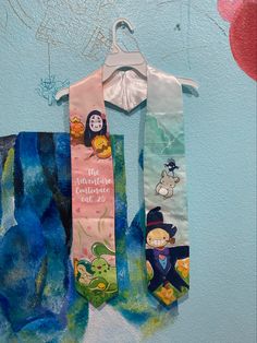 two children's neck ties hanging on a blue wall with cartoon characters painted on them