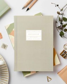 a yellow notebook sitting on top of a white table next to a cup of coffee