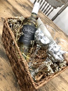 a bottle of wine sitting on top of a wooden table next to a basket filled with chocolates