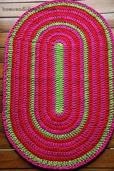 a crocheted rug is laying on a wooden floor with yarn and scissors next to it