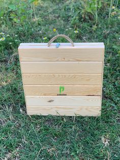 a wooden briefcase sitting on top of a lush green field