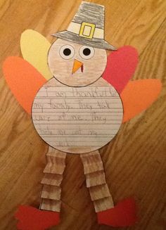 a turkey made out of construction paper on top of a wooden table with writing in it