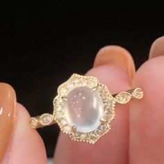 a woman's hand holding a ring with a large white stone in the middle