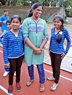 three girls are standing on a track with their arms around each other