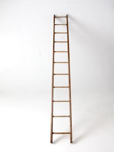 an old wooden ladder leaning against a white wall