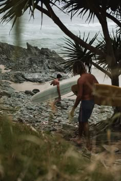 two surfers carrying their surfboards on the beach