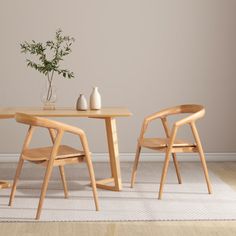 two wooden chairs sitting at a table with a vase on top of it and one chair next to the table