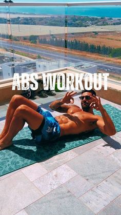 a man laying on top of a blue mat in front of a window with the words abs workout