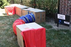 several boxes are lined up in front of a fence and gate with red tarps on them