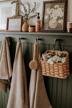 towels hanging on the wall next to a basket with flowers and other items in it