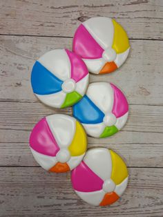 four beach ball shaped cookies sitting on top of a wooden table