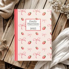 a personalized notebook with strawberries and bows on the cover, next to flowers