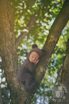 a baby in a bear suit is sleeping on a tree