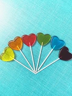 six heart shaped lollipops on a blue background