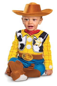 a young boy wearing a yellow shirt and cowboy hat sitting on the ground with his legs crossed