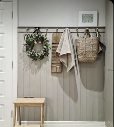 two baskets hanging on the wall next to a wooden stool and coat rack with wreaths