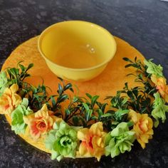 a yellow bowl sitting on top of a plate covered in flowers