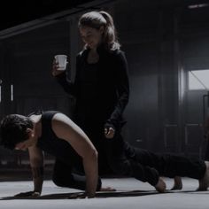 two people doing push ups on the floor with one holding a drink in his hand