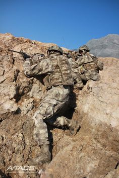 two soldiers climbing up the side of a mountain