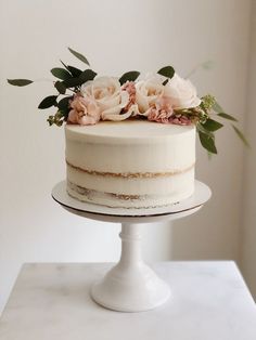 a white cake topped with flowers and greenery